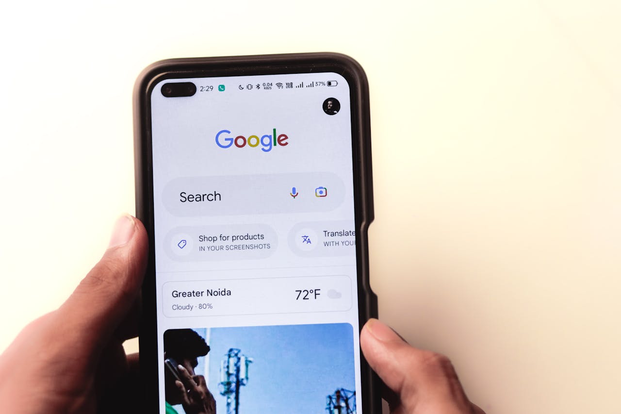 about-01 A close-up of a hand holding a smartphone with Google search displayed on the screen.